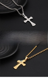 Detailed close-up of stainless steel cross necklaces in silver and gold with scroll engraving