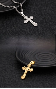 Detail of gold and silver steel cross pendants with embossed floral and heart patterns