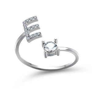 Detail of silver letter E ring featuring pavé diamonds and a claw-set solitaire stone