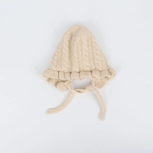 Detail of baby knit hat featuring cream white cable knit pattern and ruffled brim