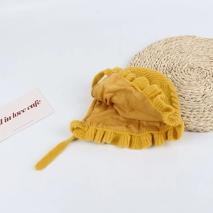 Detail view of yellow baby knit bonnet with soft ruffles and knitted chin ties