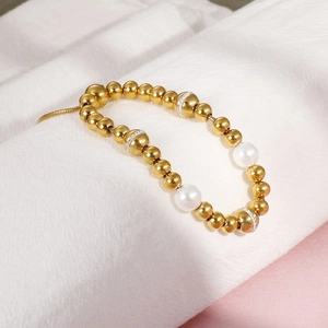 Adjustable gold bead bracelet featuring white pearls and rhinestone accents on fabric