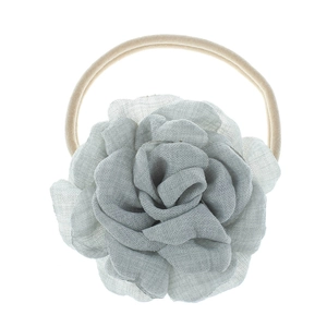 Detailed macro view of the light grey-green fabric flower on a beige elastic baby headband