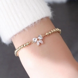 Close-up of golden adjustable wire bracelet with crystal bow charm on a model's wrist