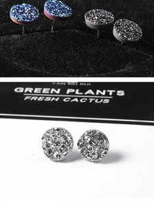Macro shot of stylish round ear studs with sparkling crystal druzy texture in blue and black