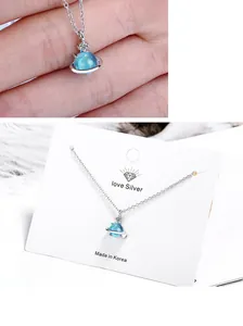 Macro detail of blue planet pendant necklace with silver orbit and zircon crystal