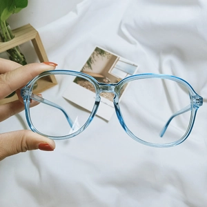 Close-up of blue transparent oversized glasses frame held against a white fabric backdrop