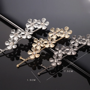 Detailed view of three metal flower hair clips with clear rhinestones and size labels