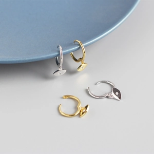 Detailed view of silver and gold geometric eye earrings with starburst on a blue plate