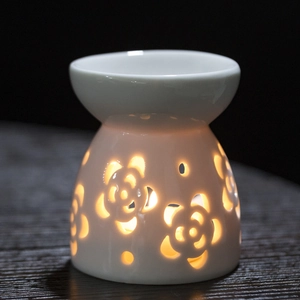 White ceramic floral cutout aromatherapy oil burner with warm candle light glowing through
