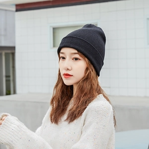 Detailed close-up of a black knit beanie being worn by a model in a natural outdoor setting