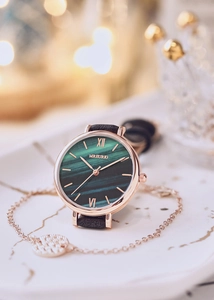 Close-up of elegant emerald green marble dial watch set with a rose gold bracelet