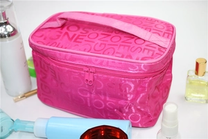 Pink travel makeup bag with handle and zipper shown with beauty products on white background