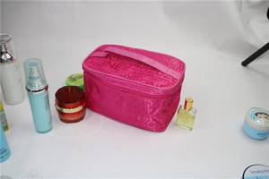 Detail of rose red rectangular cosmetic bag with top handle and cosmetic accessories