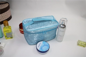 Detail of light blue vanity bag with double zippers and silver letter patterns