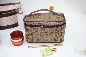 Close-up of brown cosmetic bag with SOIGNE letter pattern and sturdy handle detail