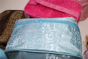Close-up of fabric cosmetic bags in blue, pink, and brown with SOIGNE letter pattern