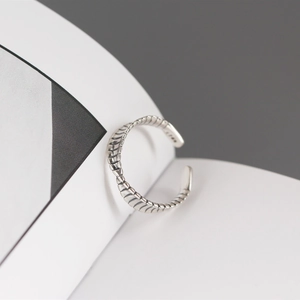 Macro detail of vintage twisted S925 sterling silver Mobius ring on white paper