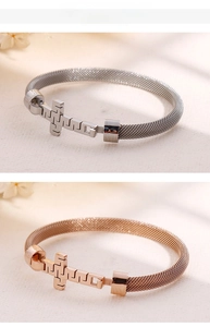 Detail of cross charm on woven mesh stainless steel bracelets in silver and rose gold
