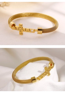 Detailed macro view of golden cross element and woven mesh band on stainless steel bracelet