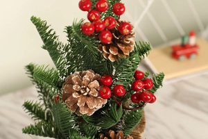 Close-up of mini Christmas tree with red berries, pine cones and snowy pine needles