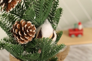 Close-up of mini Christmas tree featuring natural pine cones and soft cotton details
