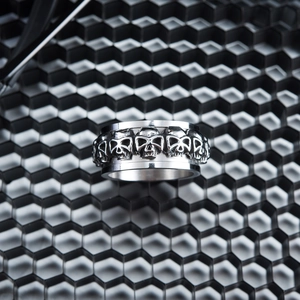 Stainless steel ring featuring rotating skull embossment over a metallic hexagonal grid