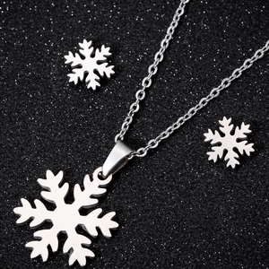 Elegantes Set aus Halskette und Ohrsteckern mit Schneeflocken auf schwarzem Hintergrund