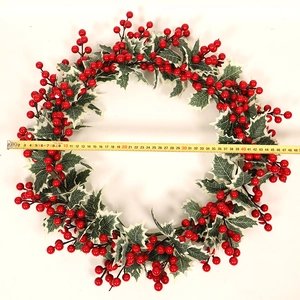 Gros plan d'une couronne de Noël de 48 cm avec baies rouges et feuilles de houx bordées de blanc