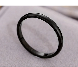 Detailed macro shot of a black polished minimalist stainless steel ring on purple fabric