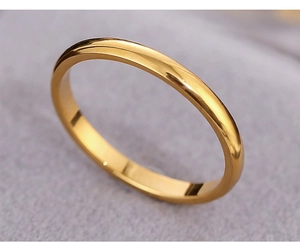 Close-up of a minimalist polished gold stainless steel band ring on a velvet base