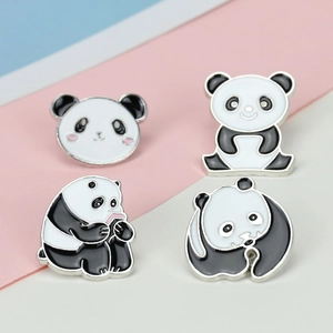 Macro shot of four cute panda enamel pins with silver metal edges on a pastel background