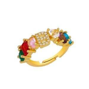 Detail of golden adjustable ring with zircon-encrusted letter B and colorful gemstones