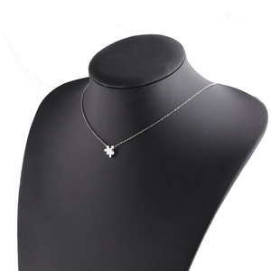 Silver puzzle piece pendant necklace on black display stand, polished stainless steel
