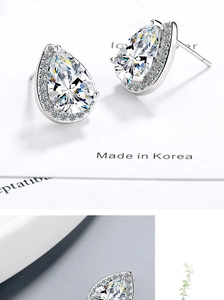 Macro shot of silver teardrop zircon earrings with halo setting and pear-cut stones