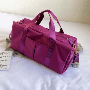 Detailed view of purple nylon gym bag with handles and shoulder strap on white linen