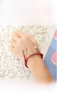 Close-up of red braided rope bracelet with heart pendant on model's wrist