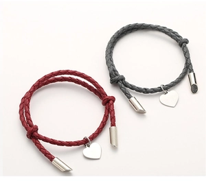 Matching red and grey braided cord bracelets with silver heart charms on white background