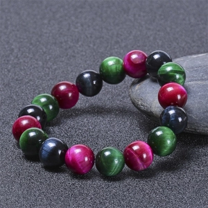 Détail macro de perles en œil de tigre naturelles rouge, vert et bleu sur fond sombre
