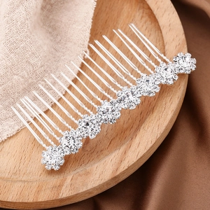 Silver bridal hair comb with rhinestone sunflowers and pearls on a wooden tray