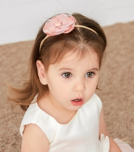 Detailed close-up of a pink fabric flower headband on a child, showing soft nylon texture
