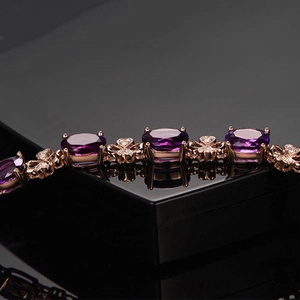 Rose gold amethyst bracelet with clover design and sparkling diamonds on black surface