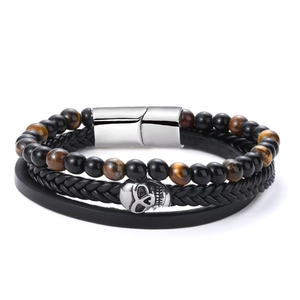 Macro detail of multilayer punk bracelet with skull charm and tiger eye stone beads