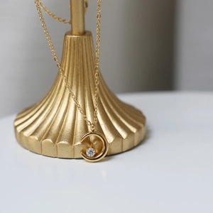 Detailed close-up of 18K gold-plated crescent moon pendant with sparkling central zircon stone