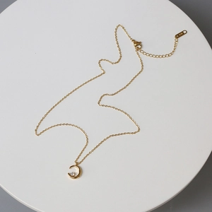 Close-up of golden crescent moon pendant with zircon and K18 tag on O-chain necklace
