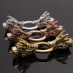 Gros plan de trois fermoirs tête de dragon en argent, bronze et or avec écailles