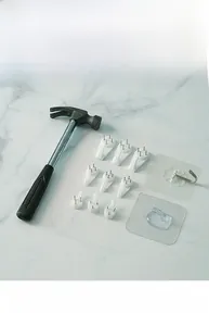 Macro shot of assorted traceless wall hooks and a metal hammer for damage-free hanging