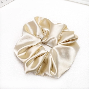 Close-up of champagne gold satin scrunchie with silky texture and elegant fabric folds