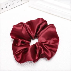 Close-up of a burgundy glossy satin scrunchie showing fabric texture and smooth sheen