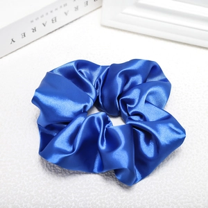 Detailed view of glossy royal blue satin scrunchie with silky smooth fabric texture